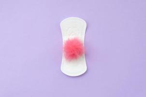 Menstrual pad and red fluffy fuzzy as a blood on violet pastel background flat lay top view photo