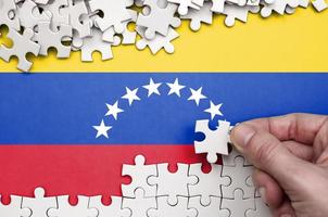 la bandera de venezuela está representada en una mesa en la que la mano humana dobla un rompecabezas de color blanco foto