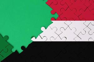 Sudan flag  is depicted on a completed jigsaw puzzle with free green copy space on the left side photo