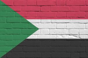 Sudan flag depicted in paint colors on old brick wall. Textured banner on big brick wall masonry background photo