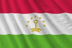 Tajikistan flag with big folds waving close up under the studio light indoors. The official symbols and colors in banner photo