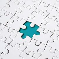Close-up texture of a white jigsaw puzzle in assembled state with missing elements forming a blue pad for text. Copy space photo