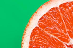 Top view of an one grapefruit slice on bright background in green color. A saturated citrus texture image photo