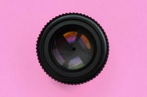 Camera lens with a closed aperture lie on texture background of fashion pastel pink color paper in minimal concept photo