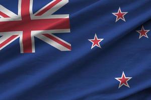 New Zealand flag with big folds waving close up under the studio light indoors. The official symbols and colors in banner photo