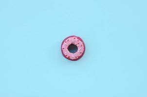 Single small plastic donut lies on a pastel colorful background. Flat lay minimal composition. Top view. photo