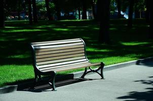 banco de madera vacío en el parque de verano contra la hierba verde foto