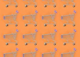 Shopping addiction, shopping lover or shopaholic concept. Many small empty shopping carts perform a pattern on a pastel colored paper background. Flat lay composition, top view photo