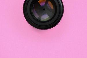 Camera lens with a closed aperture lie on texture background of fashion pastel pink color paper in minimal concept photo