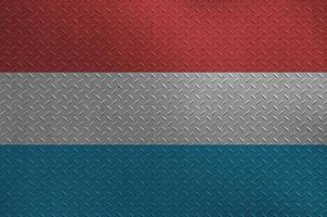 Luxembourg flag depicted in paint colors on old brushed metal plate or wall closeup. Textured banner on rough background photo