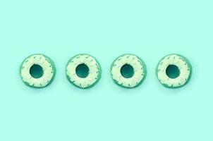 Many small plastic donuts lies on a pastel colorful background. Flat lay minimal pattern. Top view photo