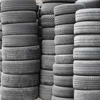 Old used tires stacked with high piles in secondary car parts shop garage photo