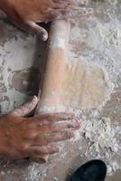 Close-up of young woman rolling dough with rolling pin photo