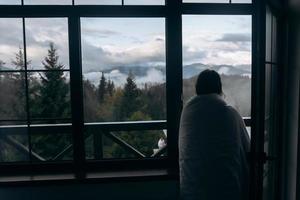 Young woman is looking through the window at the mountains photo