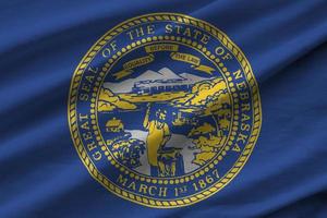 Nebraska US state flag with big folds waving close up under the studio light indoors. The official symbols and colors in banner photo