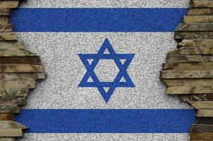 Israel flag depicted in paint colors on old stone wall closeup. Textured banner on rock wall background photo