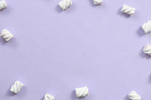 Colorful marshmallow laid out on violet paper background. pastel creative textured framework. minimal photo