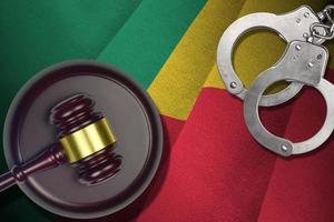 Benin flag with judge mallet and handcuffs in dark room. Concept of criminal and punishment, background for judgement topics photo