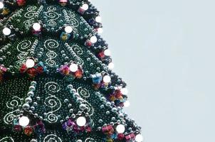 A fragment of a huge Christmas tree with many ornaments, gift boxes and luminous lamps. Photo of a decorated Christmas tree close-up with copy space