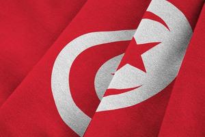 Tunisia flag with big folds waving close up under the studio light indoors. The official symbols and colors in banner photo