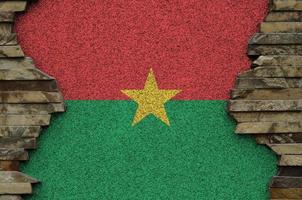 Burkina Faso flag depicted in paint colors on old stone wall closeup. Textured banner on rock wall background photo