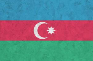 Azerbaijan flag depicted in bright paint colors on old relief plastering wall. Textured banner on rough background photo