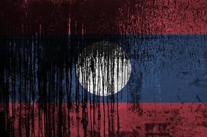 bandera de laos representada en colores de pintura en el primer plano de la pared del barril de petróleo viejo y sucio. banner texturizado sobre fondo áspero foto