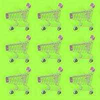 Shopping addiction, shopping lover or shopaholic concept. Many small empty shopping carts perform a pattern on a pastel colored paper background. Flat lay composition, top view photo