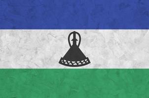 Lesotho flag depicted in bright paint colors on old relief plastering wall. Textured banner on rough background photo