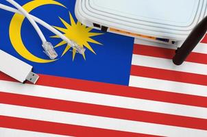 Malaysia flag depicted on table with internet rj45 cable, wireless usb wifi adapter and router. Internet connection concept photo