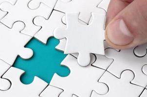 The human hand fills the last missing elements of the surface from the jigsaw puzzle. The concept of the completion of the initiated cases photo