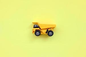 Small yellow toy truck on texture background of fashion pastel yellow color paper in minimal concept photo