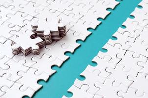 The blue path is laid on the platform of a white folded jigsaw puzzle. The missing elements of the puzzle are stacked nearby. Texture image with space for text photo