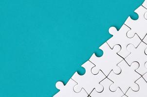 Fragment of a folded white jigsaw puzzle on the background of a blue plastic surface. Texture photo with copy space for text