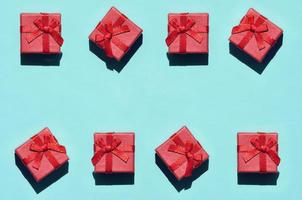Many small red pink gift boxes on texture background of fashion trendy pastel blue color paper in minimal concept. Abstract pattern photo