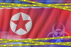 North Korea flag and Covid-19 quarantine yellow tape. Coronavirus or 2019-nCov virus concept photo