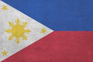 Philippines flag depicted in bright paint colors on old relief plastering wall. Textured banner on rough background photo