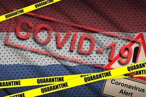 Netherlands flag and Covid-19 quarantine yellow tape with red stamp. Coronavirus or 2019-nCov virus photo