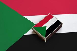 Sudan flag  is pictured on a matchbox that lies on a large flag photo