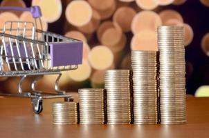 Empty shopping cart and money stacks in growth graph on background of colored bokeh christmas lights photo