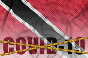 Trinidad and Tobago flag and Covid-19 inscription with orange quarantine border tape. Coronavirus or 2019-nCov virus concept photo