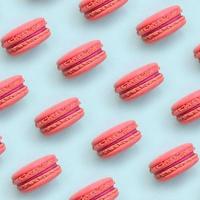 Pink dessert cake macaron or macaroon on trendy pastel blue background top view. Flat lay pattern composition photo