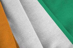 Ivory Coast flag with big folds waving close up under the studio light indoors. The official symbols and colors in banner photo