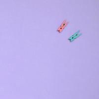 Two colored wooden pegs lie on texture background of fashion pastel violet color paper in minimal concept photo