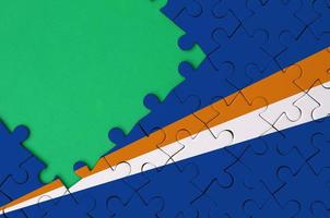 Marshall Islands flag  is depicted on a completed jigsaw puzzle with free green copy space on the left side photo