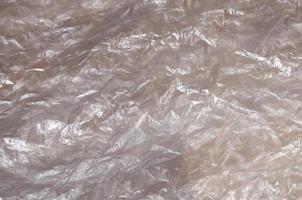 textura de la superficie de celofán blanco arrugado transparente a la luz del sol. concepto de materiales para embalaje, protección del producto contra daños foto