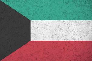 Kuwait flag depicted in bright paint colors on old relief plastering wall. Textured banner on rough background photo