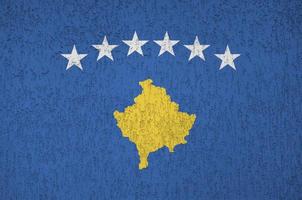 Kosovo flag depicted in bright paint colors on old relief plastering wall. Textured banner on rough background photo