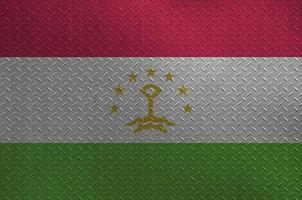 Tajikistan flag depicted in paint colors on old brushed metal plate or wall closeup. Textured banner on rough background photo