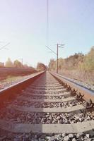 Autumn industrial landscape. Railway receding into the distance among green and yellow autumn trees photo